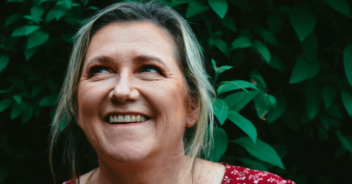 Smiling women in front of greenery